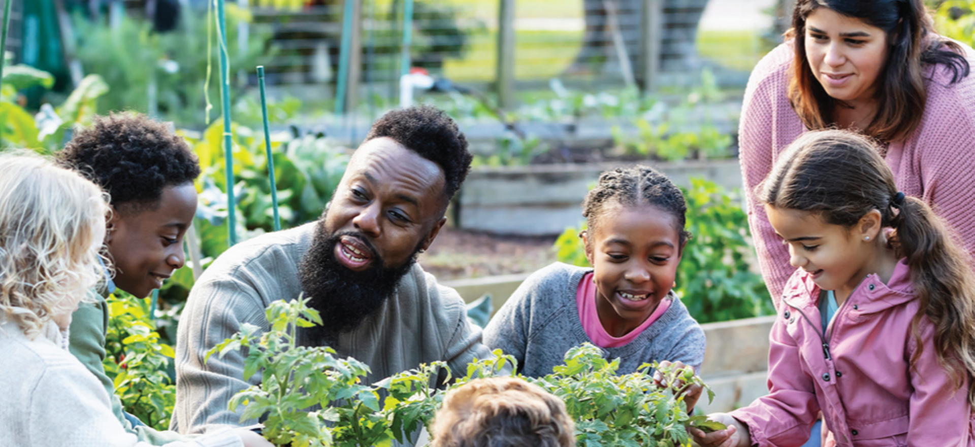 A multiracial family, representing ALICE, gather around in a garden as one parent talks to the children